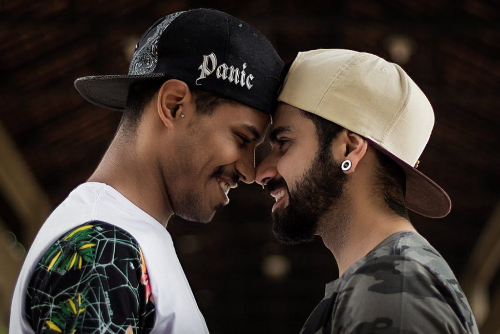 Two men standing in front of one another, smiling, head to head, nose to nose.