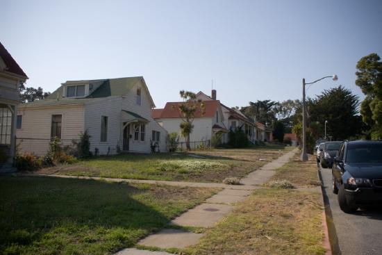 A neighborhood with homes and cars parked in the street.