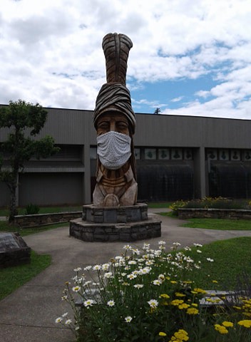 A totem with a Cherokee wearing a mask.