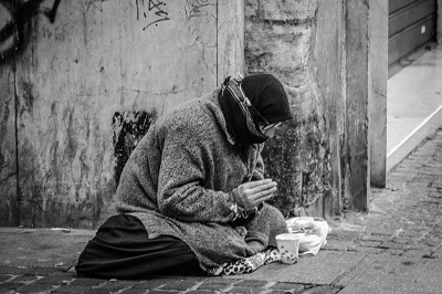 A man praying on a sidewalk.