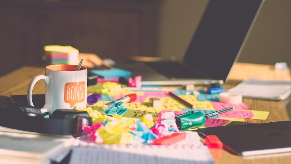 A cluttered desk strewn with papers and sticky notes.