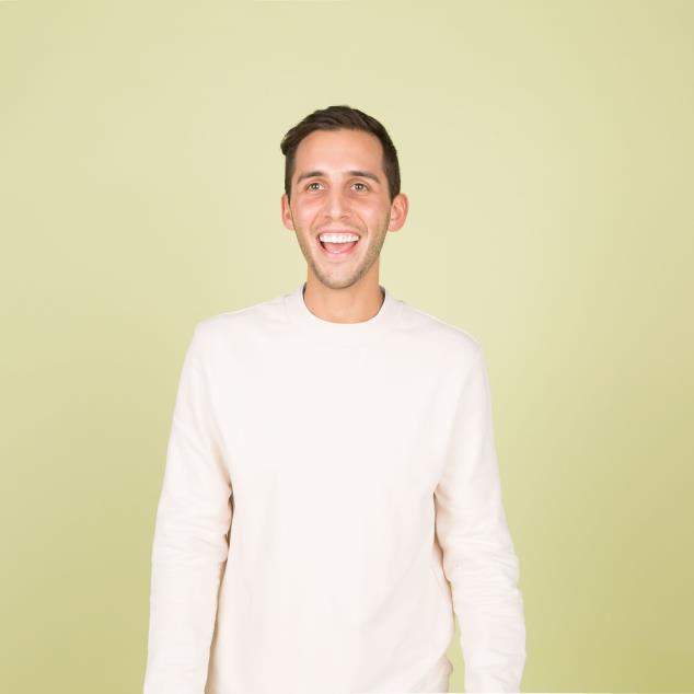 A man poses in front of a white screen.