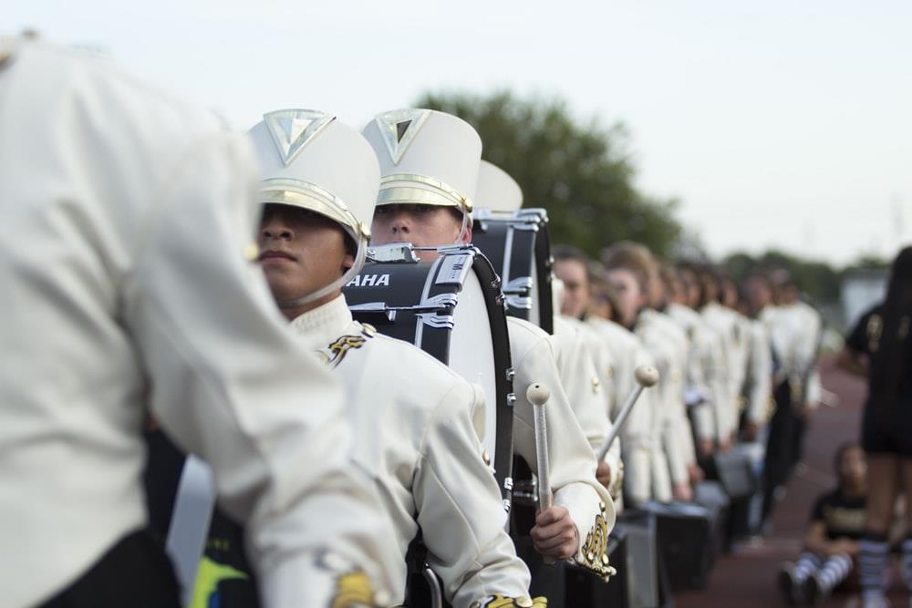 A band marching in white uniforms.