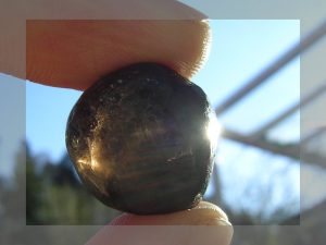 A rounded pebble of dark obsidian, known as an Apache Tear.