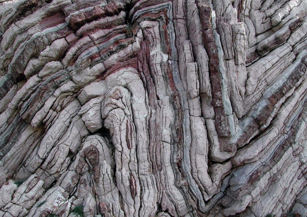 Layers of rock in an outcrop are folded together like an accordion. These types of folds are possible due to metamorphism. This