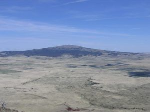 A large, shallow sloped volcano in the New Mexico desert.