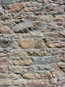 A wall made of granite bricks cemented together