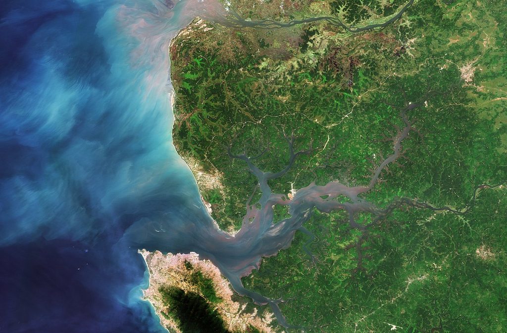 This is an aerial view of the Sierra Leone River estuary that shows the river and side channels entering the ocean, with source waters swirling in different colors.