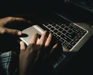 Hands resting over a laptop keyboard and trackpad.