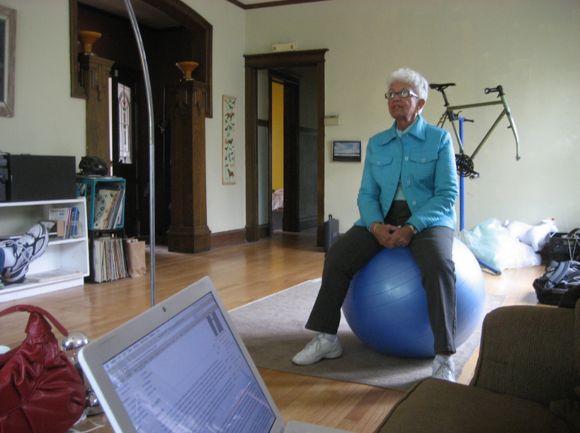 An older adult sitting on a yoga ball