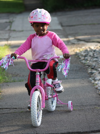 child riding bike with training wheels on