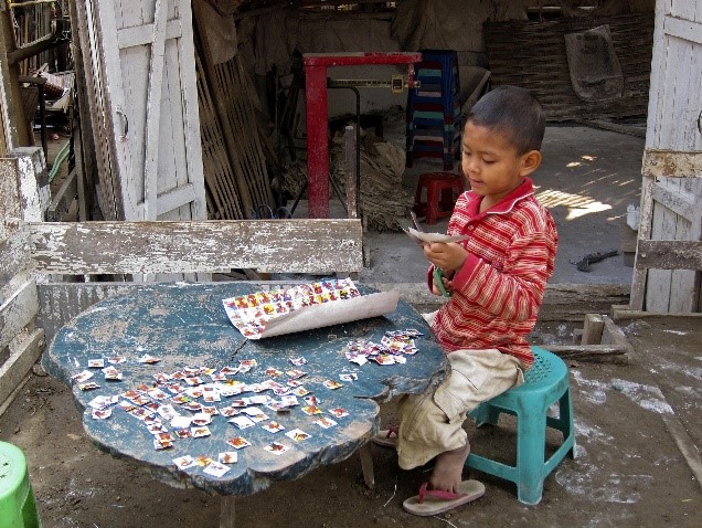 Child sitting outside cutting paper.