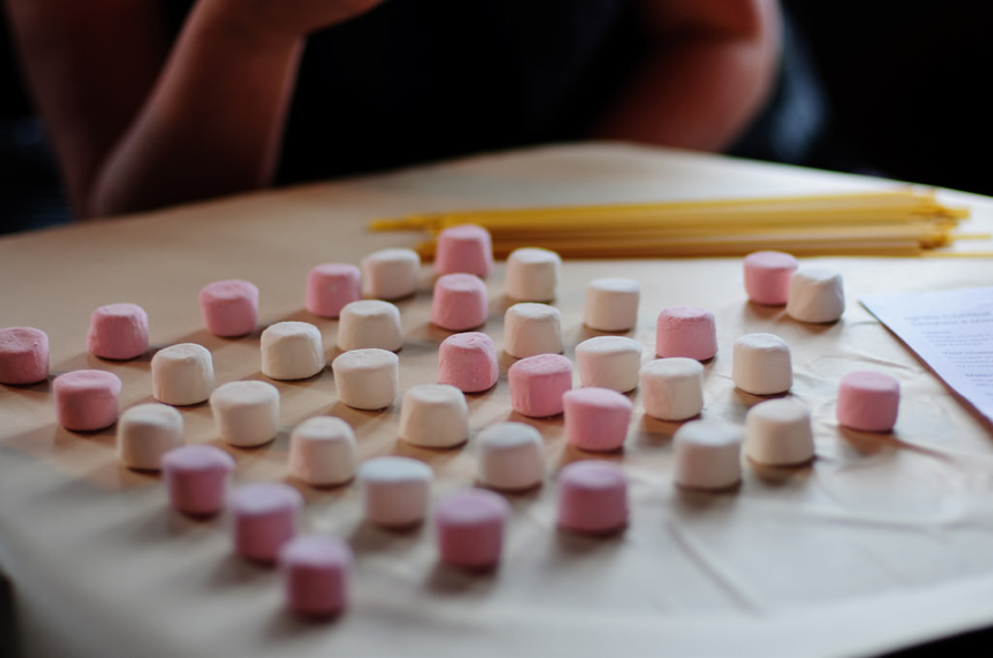 Several pink and white marshmallows laid out on a counter.