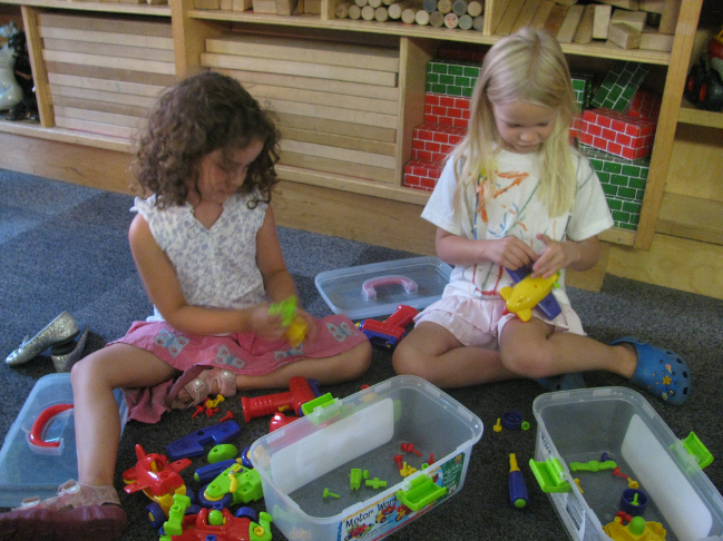 two girls playing with blocks on the floor