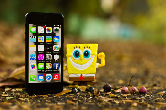 A photo of a smartphone and spongebob toy.