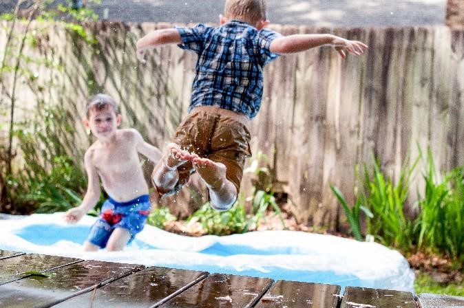 two kids jumping on trampoline outside