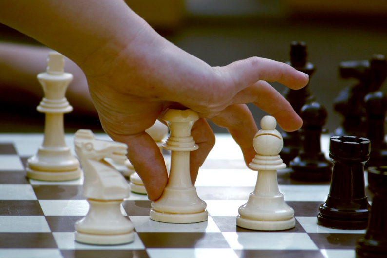 child's hand playing on chess board