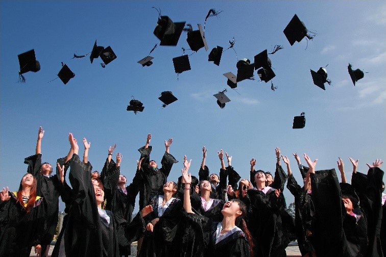 graduates in regalia tossing up up their mortar board caps