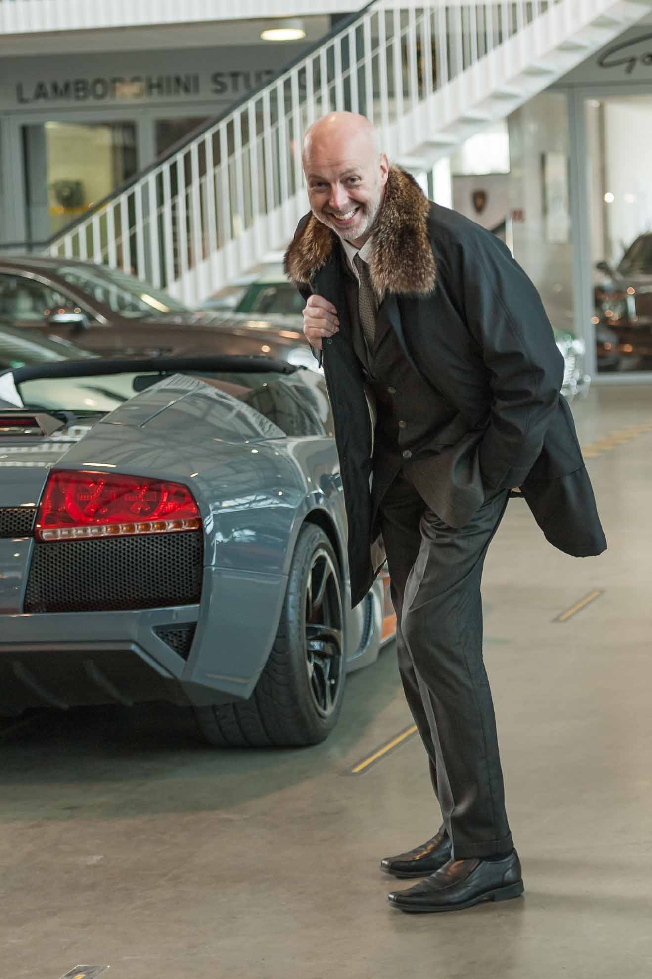 Middle aged man standing in front of sports car