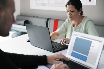 two adults working on their laptops