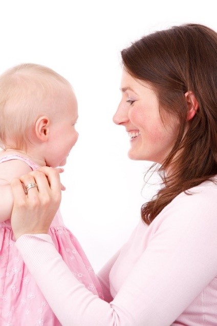 infant smiling looking at adult smiling back