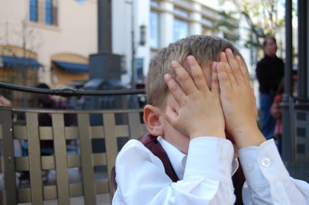 child hiding face - covered with hands