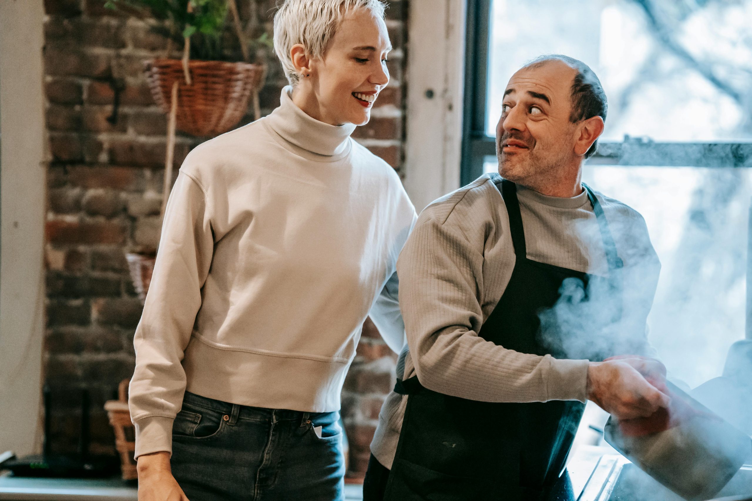 Smiling middle aged multiracial spouses preparing dinner in kitchen