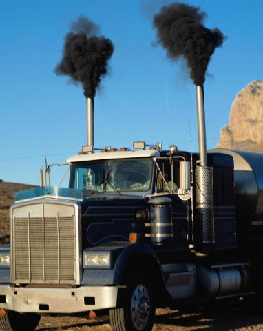 Exhaust pipes on a large truck emit thick clouds of pollutants