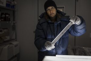 Photo of a scientist holding a cylinder that is about 2 feet long and 3 inches wide