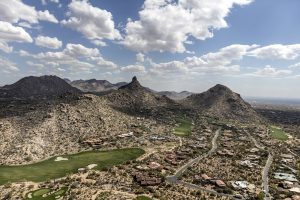 Aerial photo of a suburb and golf course at the base of a desert mountain range