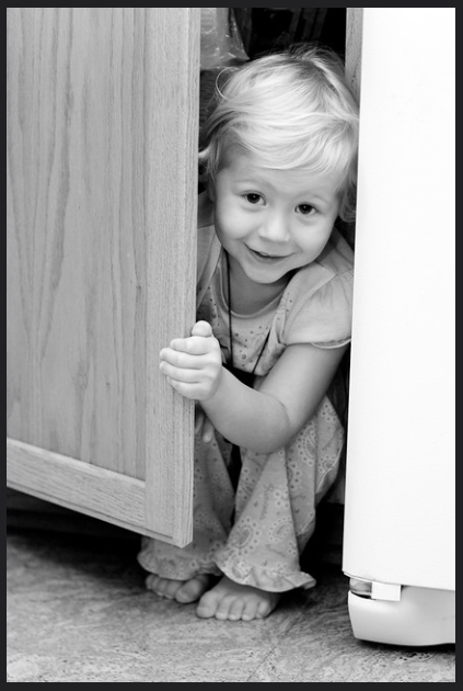 Child peeking out from a cupboard