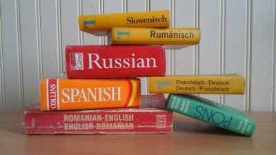 Stack of red, yellow, orange and green foreign language dictionaries.