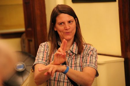 A female sign language interpreter is signing to an audience.