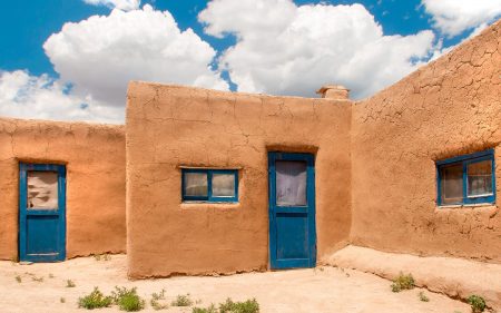 A tan adobe home with deep blue windows frames and door.