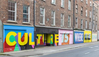 Culture is where we are is painted on a building in bright colors.