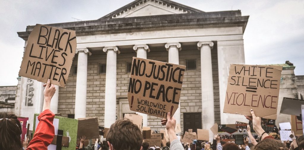 black lives matter protest. three cardboard posters showing: black lives matter, no justice/ no peace, white silence=violence