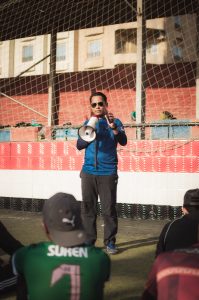 Man uses megaphone to give a speech to a kids sports team.