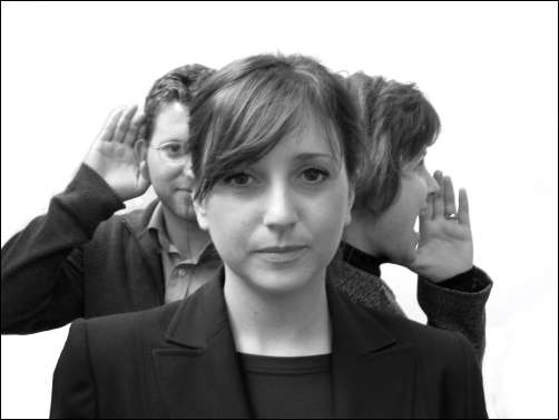 Woman with two people listening and talking behind her