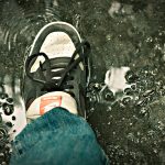 A Nike Air shoes stepping on a water puddle during rain