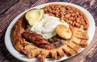 breakfast of eggs, bread, sausage, avocado, and beans on a large plate