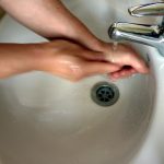 hands being washed in a white porcelain sink