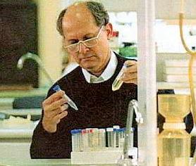 Manuel Elkin Patarroyo Murillo observes a vial while holding another in his hand