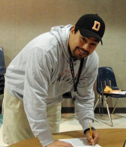 photo of a man standing at a table writing on a paper