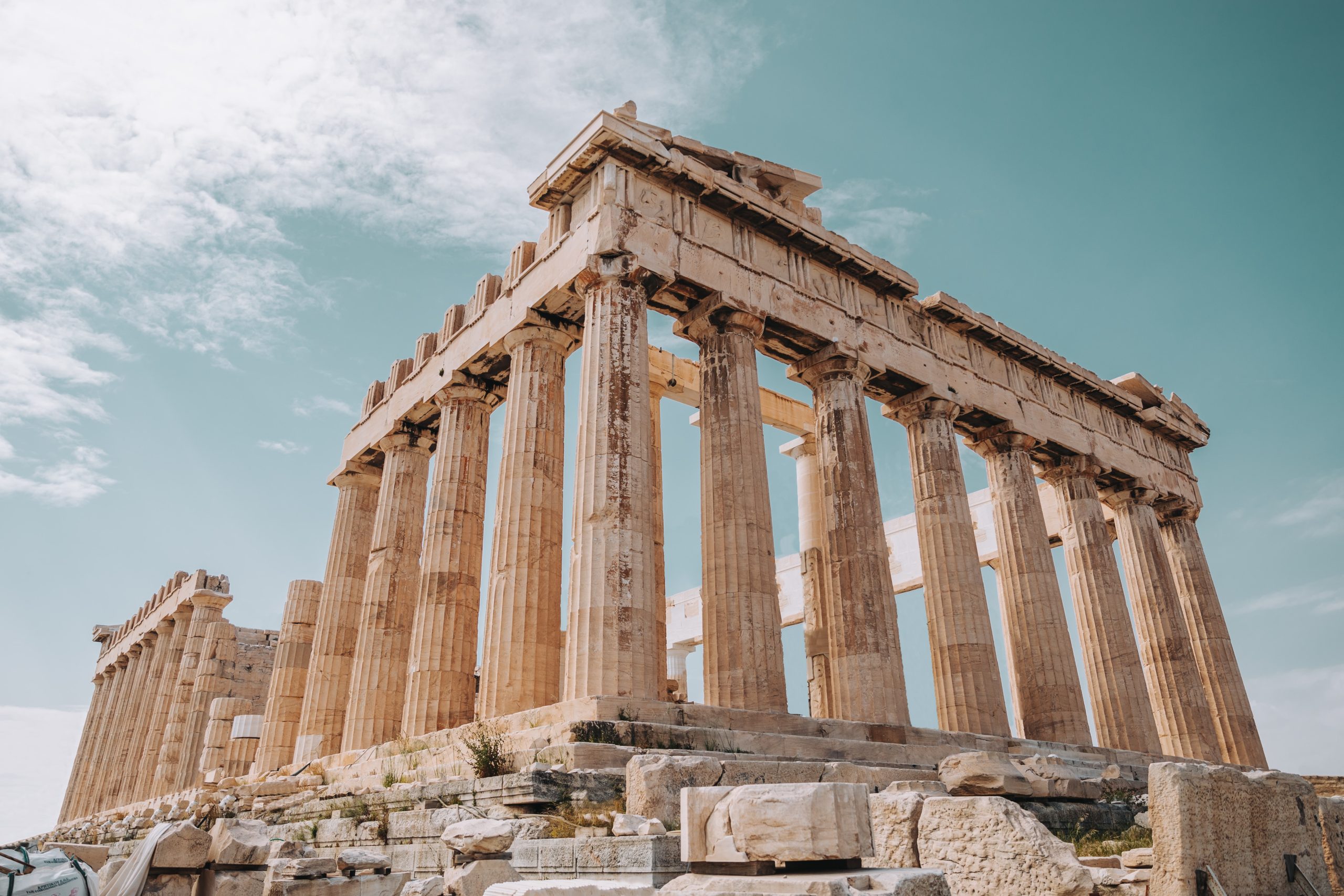 The Athens Acropolis, an ancient ruin with tall off-white pillars holding up the remains of a roof support in a rectangular shape.