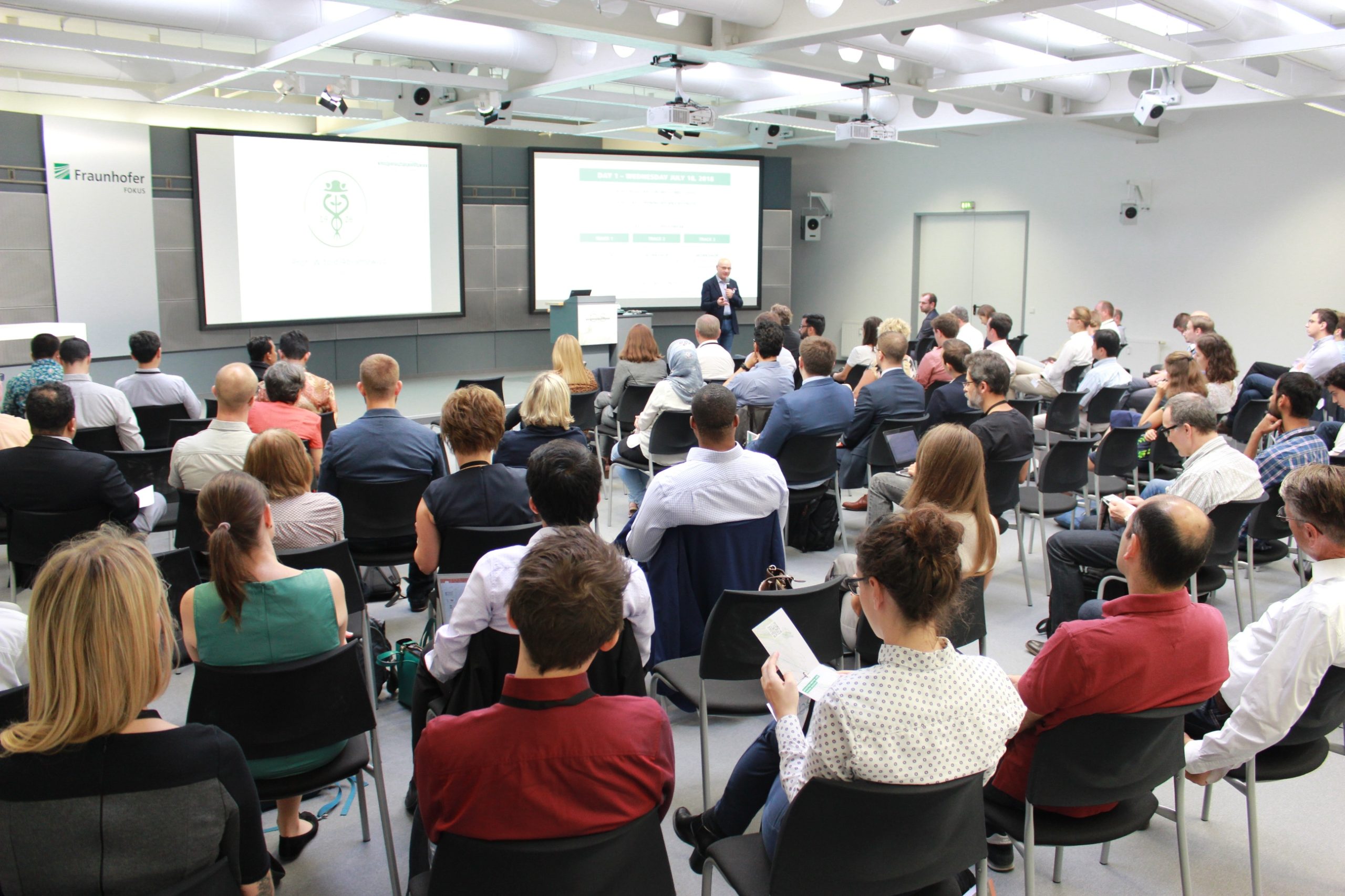 A conference with about 30 people sitting and watching a business presentation.