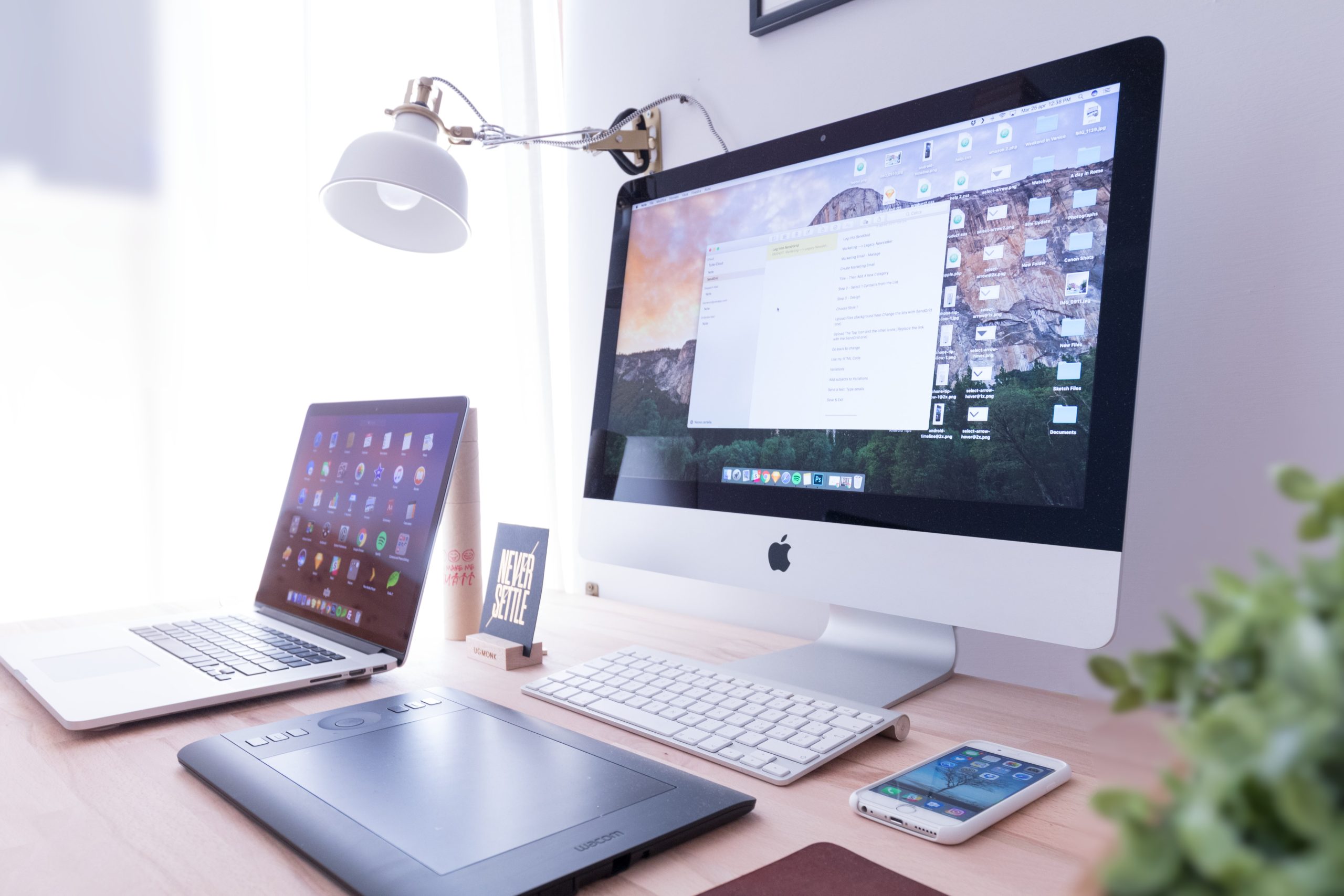 A computer, laptop, smartphone, keyboard, and touch pad mouse on a table.