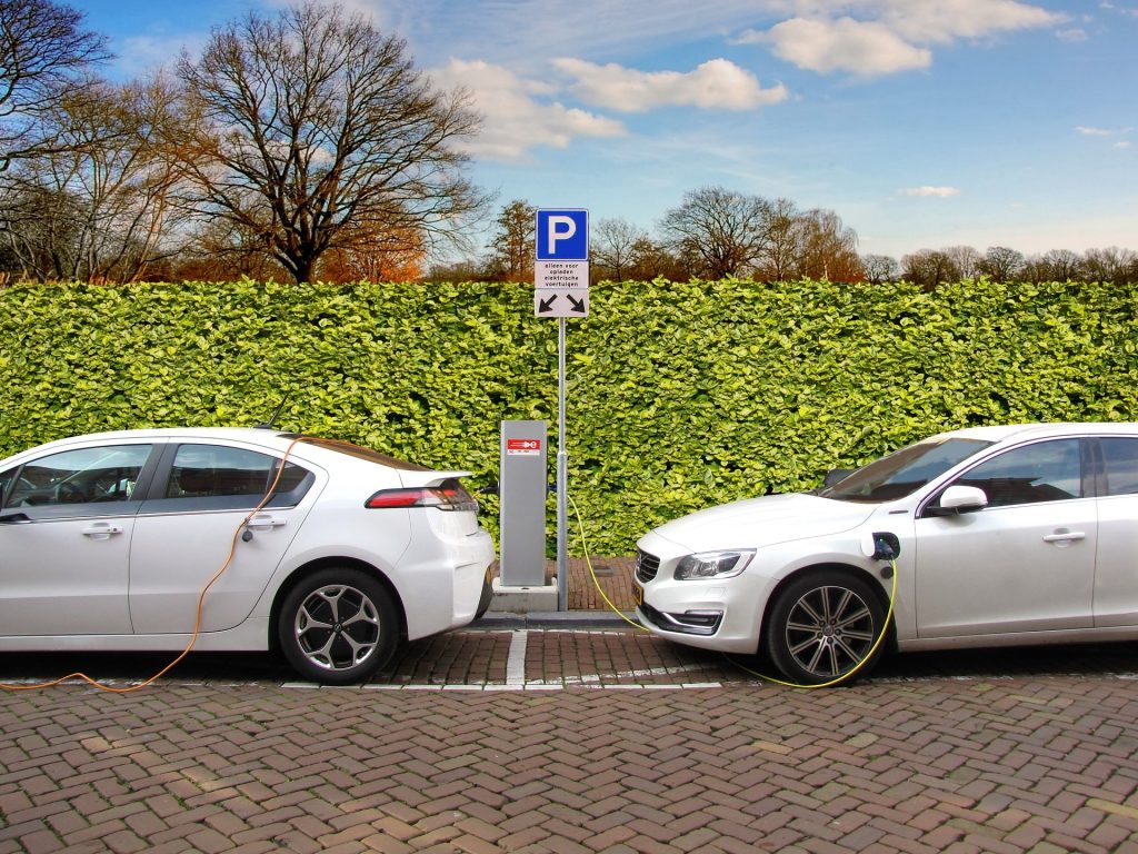 Two white electric hybrid cars parking at a charging station.