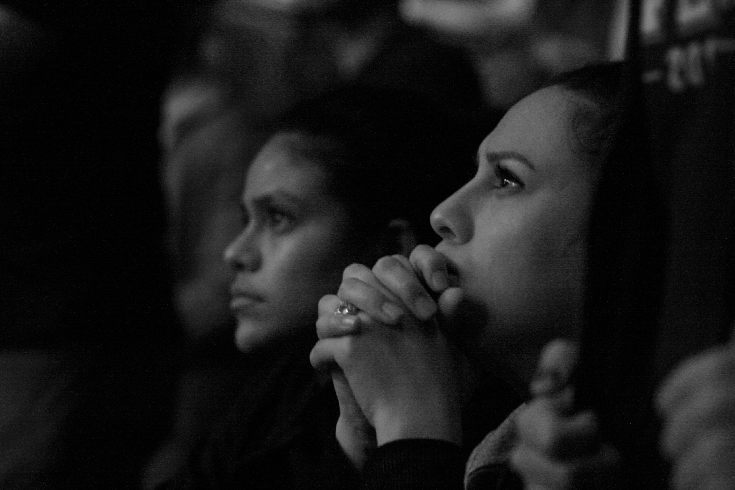 A group of women praying and listening to a speaker.