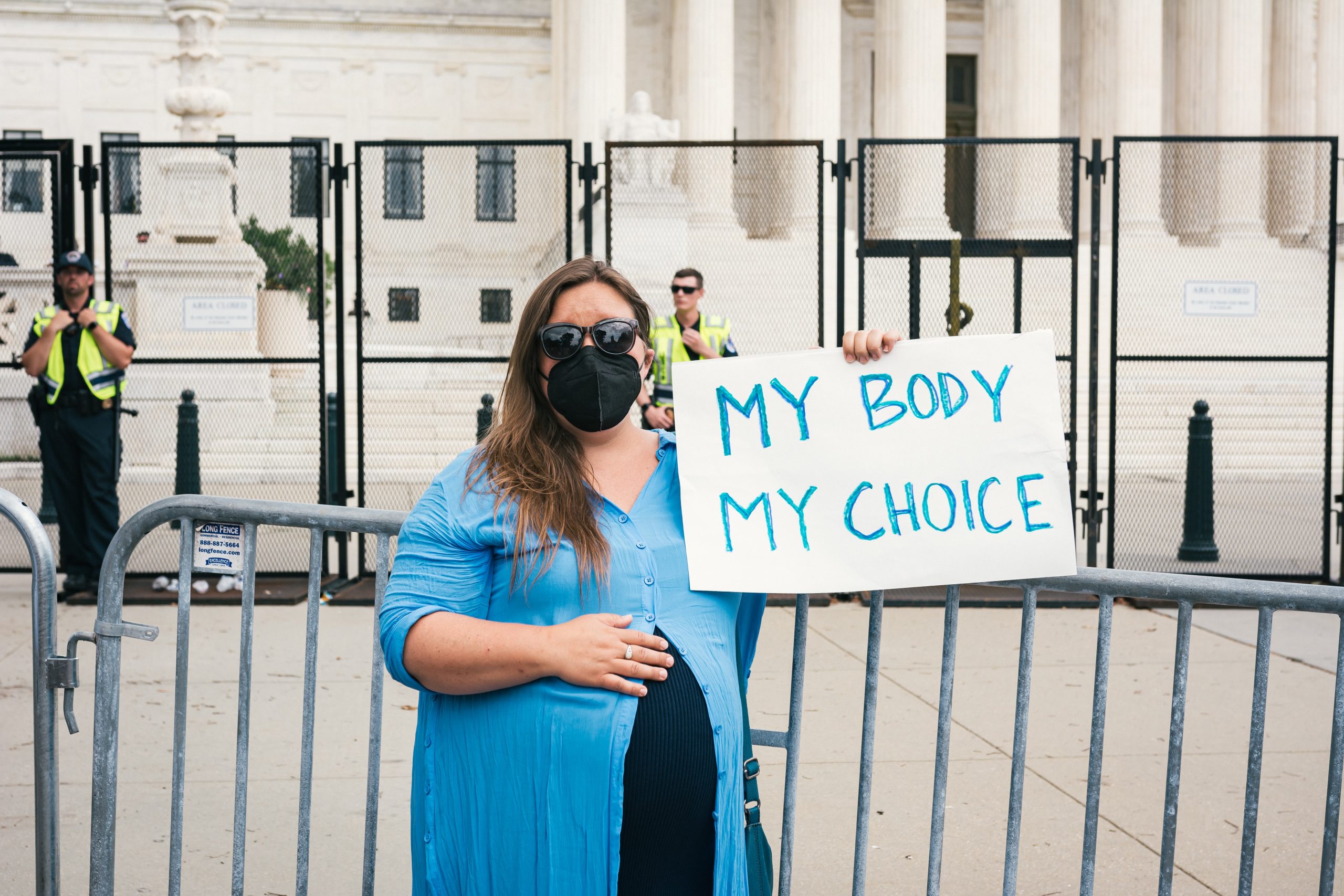 A woman standing and holding a white paper board that says “My body, my choice.”