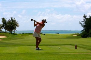 A woman swinging at a golf ball.